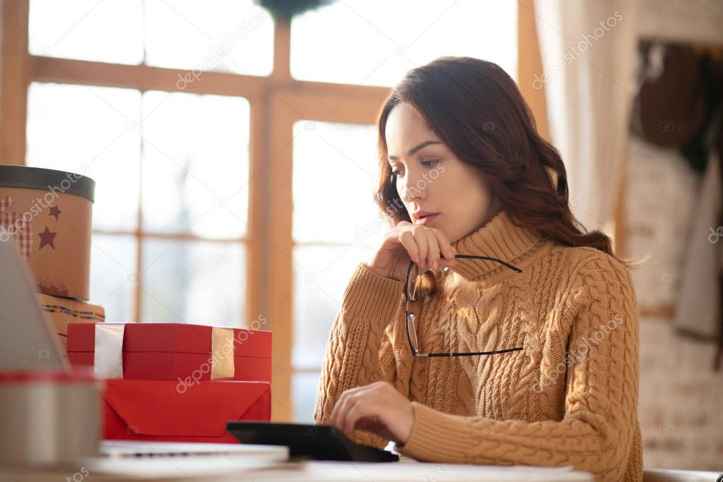 Cute woman in knitted sweater sitting at the table