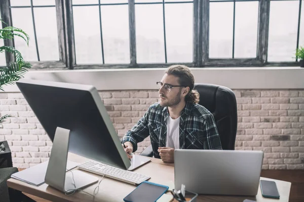 Young bearded man in eyeglasses looking concentrated — Stock Photo, Image