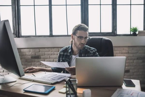 Young man in eyeglasses looking busy and involved — Stock Photo, Image