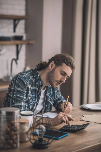 Uomo dai capelli lunghi che fa calcoli precisi per la sua attività . — Foto Stock