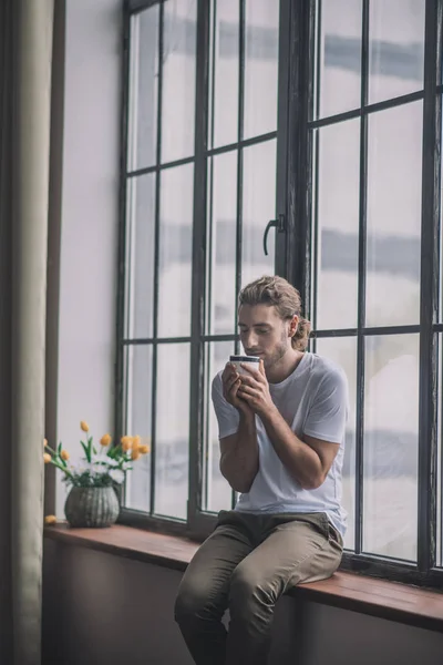 Energetic long-haired man drinking his morning coffee. — Stock Photo, Image