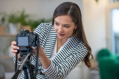 Beautiful young woman setting up the camera clipart