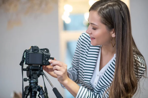 Positif femme aux cheveux longs appuyant sur un bouton sur la caméra — Photo