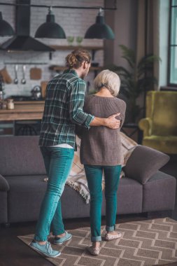 Kotlu genç adam annesini destekliyor.