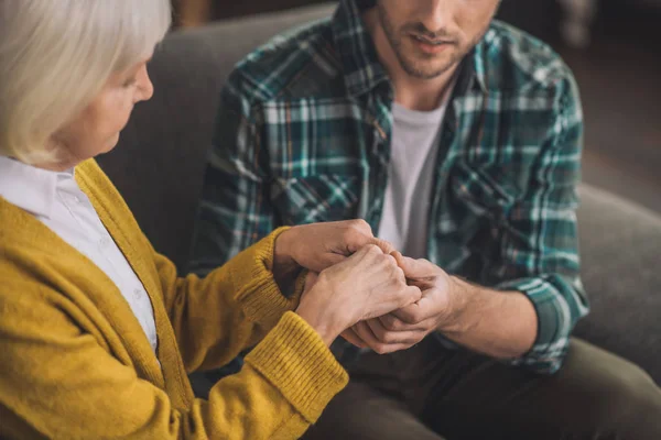 Young handsome man holding his moms hands with love — Stock Photo, Image