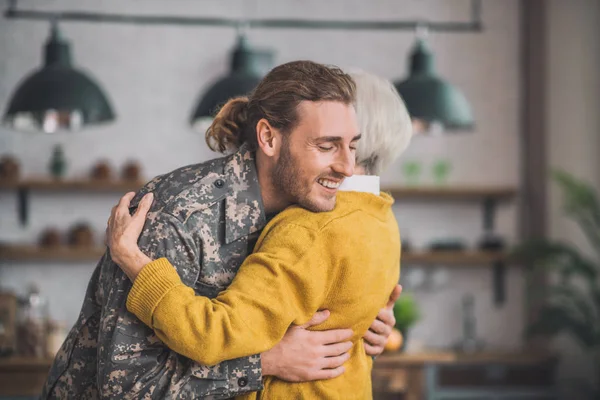 Young happy man in camouflage hugging his mom — Stock Photo, Image