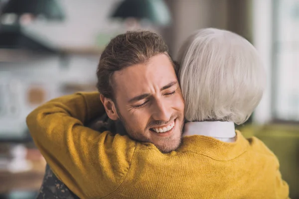 Joven hombre guapo en camuflaje abrazando a su madre — Foto de Stock