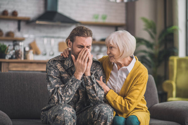 Young handsome man in camouflage looking stressed