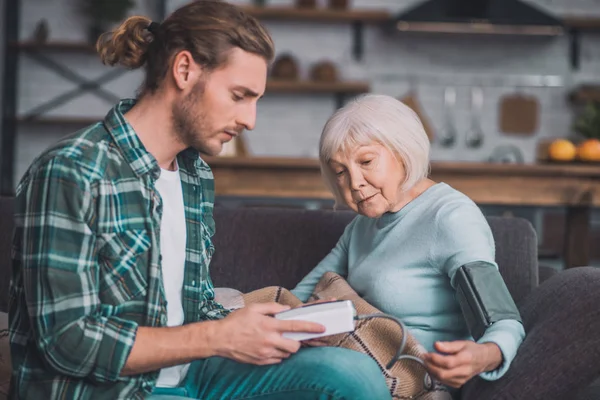 Ung man i jeans håller tonometer i sina händer — Stockfoto