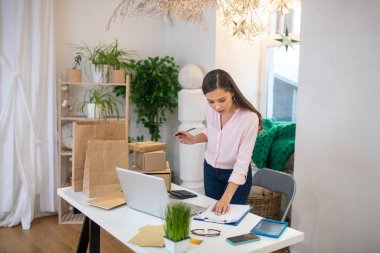 Ciddi meşgul bir kadın notlarına bakıyor.