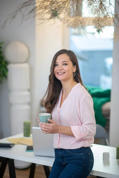 Happy young woman standing with a cup of coffee — 스톡 사진