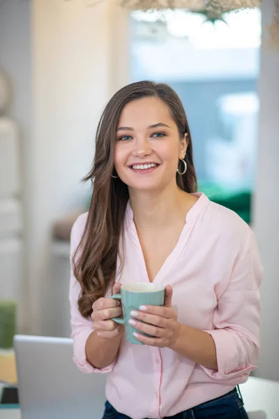 Mujer atractiva alegre sosteniendo una taza de café — Foto de Stock