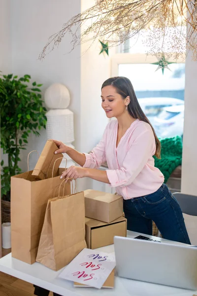 Mujer joven bien parecido mirando las bolsas con regalos — Foto de Stock