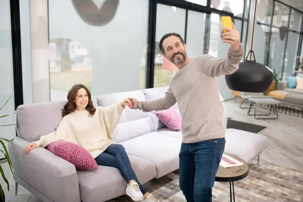 Casal se divertindo no salão de móveis fazendo selfie — Fotografia de Stock