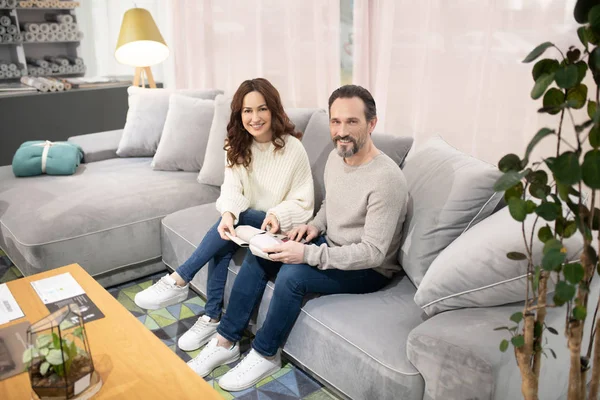 Uomo e donna seduti sul divano in un salone di mobili — Foto Stock
