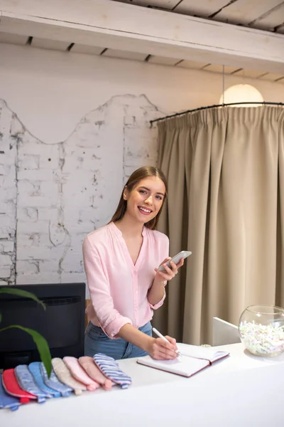 Administrador de atelier sorrindo trabalhando com clientes via telefone — Fotografia de Stock