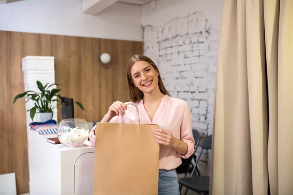 Administrador de loja sorrindo dando um item embalado para um cliente — Fotografia de Stock