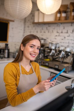 Gülümseyen barista tableti kullanarak internetten sipariş alıyor.