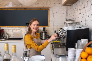 Espresso kahve makinesi kullanan gülümseyen genç barista.