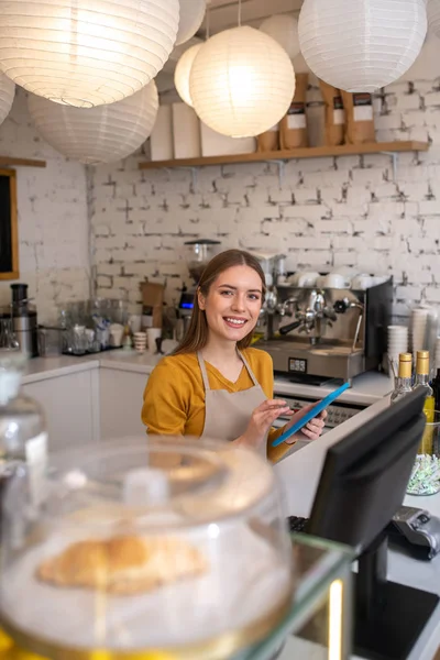 Веселый работник кафе принимает заказы через планшет — стоковое фото