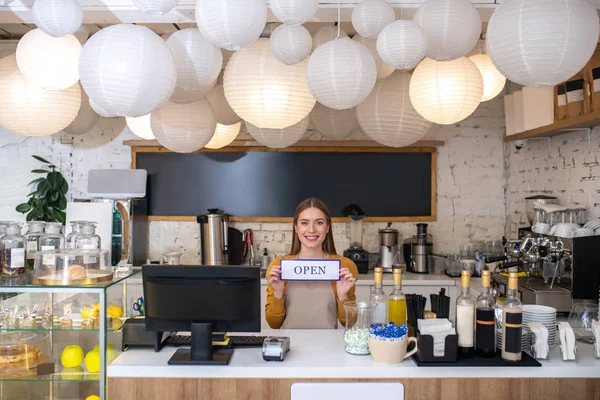 Glimlachende caféhouder met het open bord in een nieuw café — Stockfoto