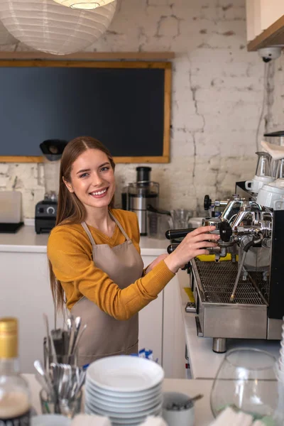 Lachende barista met behulp van professionele apparatuur voor haar werk — Stockfoto