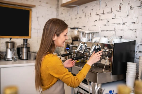 Barista sonriente de pelo largo usando una máquina de café profesional — Foto de Stock