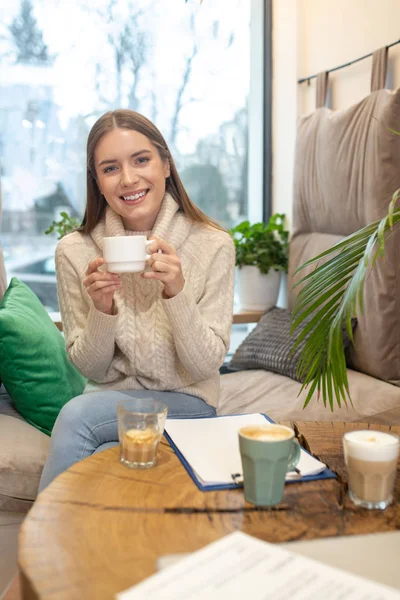 Smiling woman drinking a lot of coffee while working — Stock Photo, Image