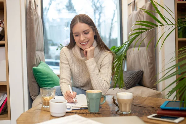 Vrouw die veel koffie drinkt terwijl ze creatief werk doet — Stockfoto