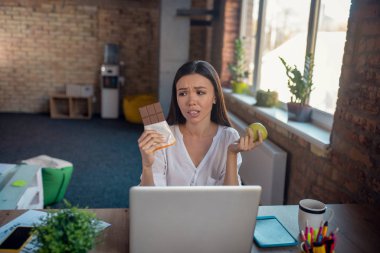Üzgün genç kadın çikolatayı seçmek istiyor.