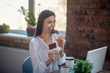 Çikolata yiyen pozitif, genç bir kadın.