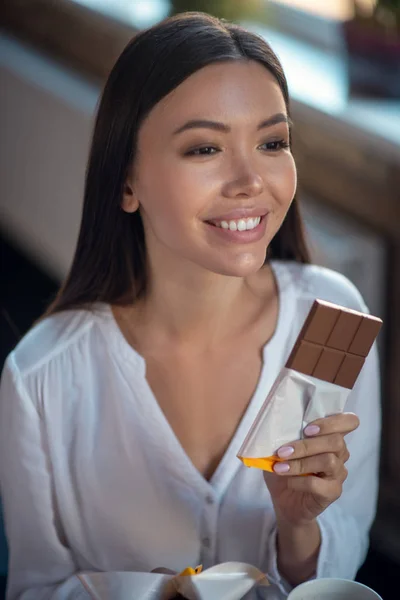 Gesicht einer glücklichen jungen Frau, die Schokolade isst — Stockfoto