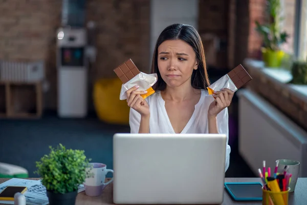 Bonita mujer triste mirando sosteniendo dos barras de chocolate — Foto de Stock