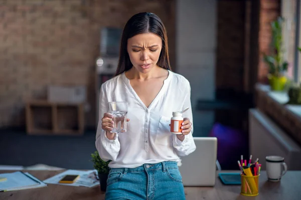 Cheerless young woman holding pills in her hand — 스톡 사진