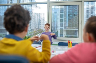 Öğrenci arkadaşlarına kelimelerin anlamını gösteriyor.