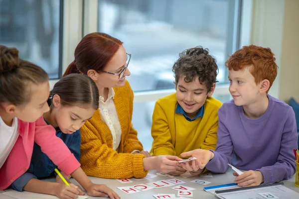 Smiling teacher explaining the task to her students a school — Stock Photo, Image