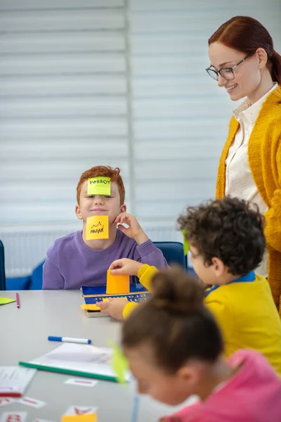 Smiling teacher helping pupils playing vocabulary game — Stock Photo, Image