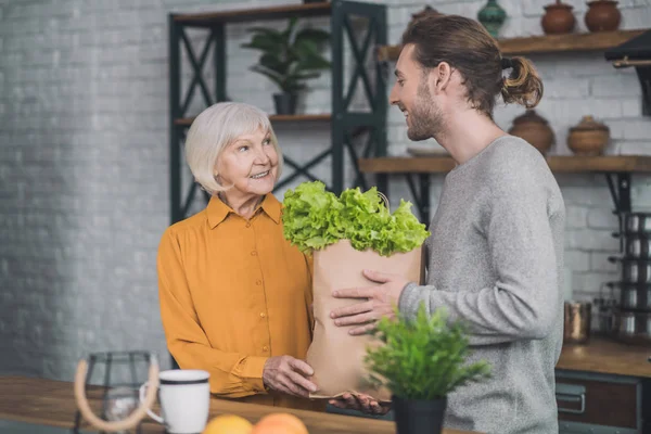 Unga leende man och hans mamma gör sig redo för middag — Stockfoto