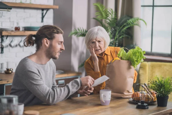 Grey-haired mom and her son discussing prices for food — 스톡 사진