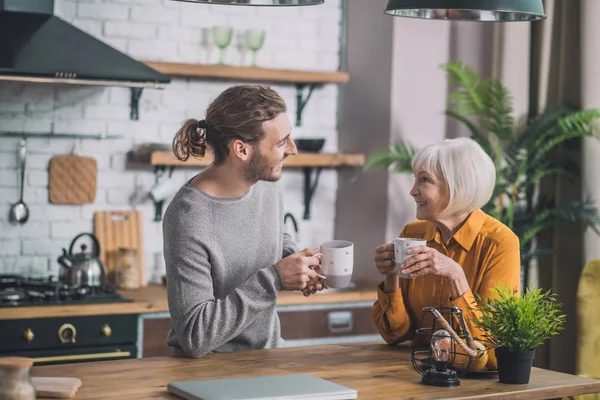 Grauhaarige Mutter und ihr Sohn sitzen in der Küche — Stockfoto