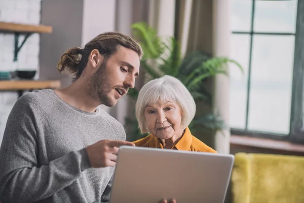 Grauhaarige Mutter und ihr Sohn diskutieren Online-Shopping-Varianten — Stockfoto