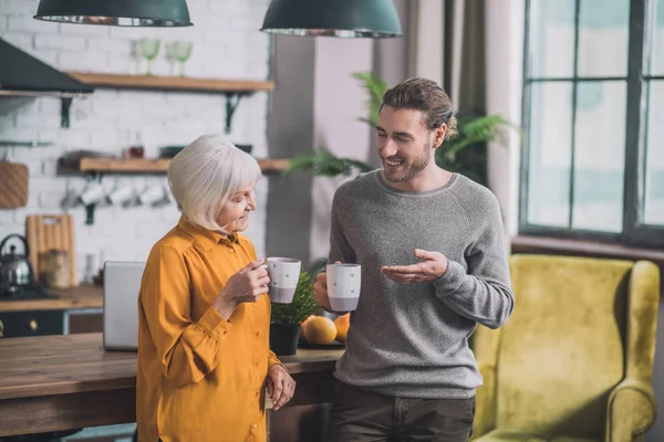 Joven hombre guapo con camisa gris y su madre discutiendo algo —  Fotos de Stock