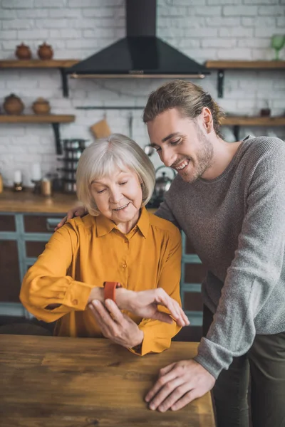 Guapa anciana en amarillo poniéndose un reloj inteligente — Foto de Stock