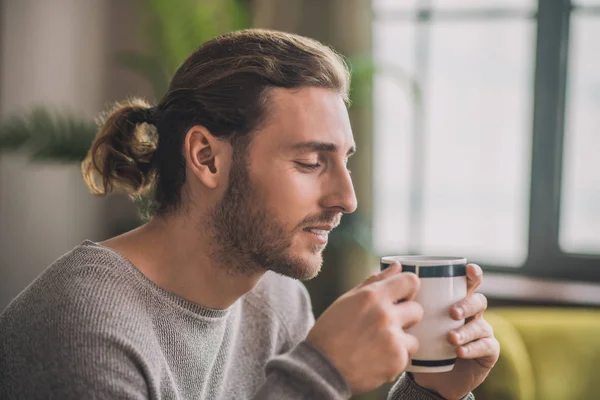 Joven hombre guapo barbudo en gris tomando café — Foto de Stock