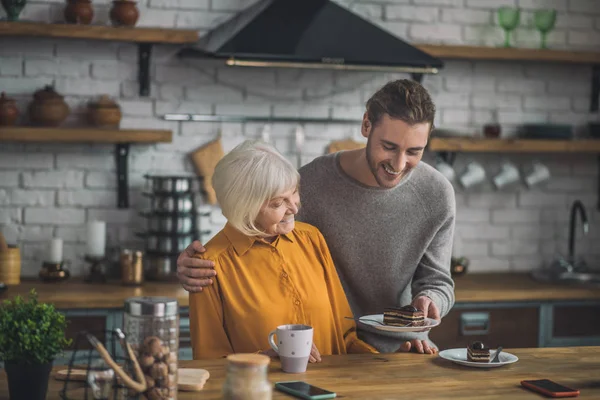 Mutter im gelben Hemd und ihr Sohn haben Spaß beim gemeinsamen Essen von Schokoladendessert — Stockfoto