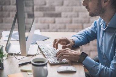 Mavi gömlekli genç adam bir şeyler yazıyor.