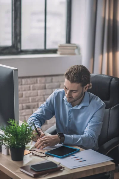 Joven hombre de negocios barbudo con camisa azul trabajando en proyecto — Foto de Stock