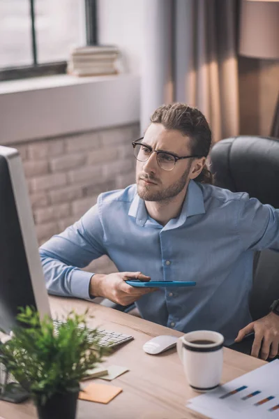 Hombre barbudo joven en camisa azul mirando atento — Foto de Stock