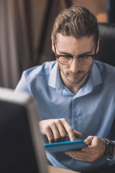 Hombre barbudo joven en camisa azul tocando la pantalla de la tableta —  Fotos de Stock