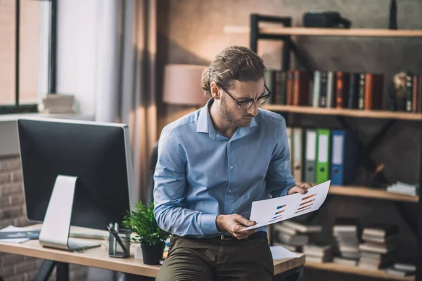 Young bearded man in blue shirt looking at the draft — 스톡 사진